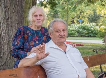 Deda sedi na klupi, a baba stoji iza njega