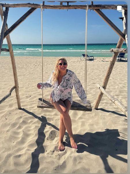 Dea Đurđević na plaži na Kubi, sedi na ljuljašci i ljulja se bosa sa naočarima za sunce