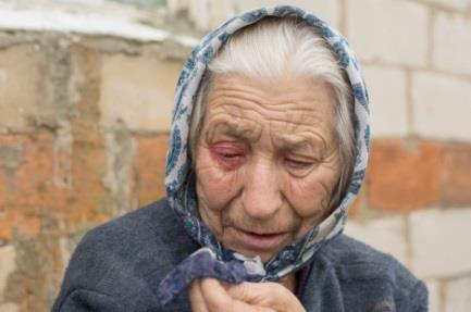 Uplakana baka sa maramom na glavi u dvorištu