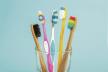 stockphotosetoftoothbrushesinglassonbluebackgroundconcepttoothbrushselectionbambooecofriendly1204882069.jpg