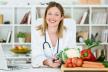 stockphotoportraitofbeautifulsmilingnutritionistlookingatcameraandshowinghealthyvegetablesinthe1167335005-23-12-2019.jpg