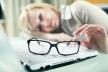 stockphotowomanwithtiredeyeswithherglassesofflyingonthetablenexttolaptopfocusedonglasses92242648.jpg