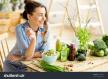 stockphotoyoungandhappywomaneatinghealthysaladsittingonthetablewithgreenfreshingredientsindoors622381814.jpg