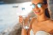 stockphotoyoungwomandrinkingsparklingwaterfromtransparentbottleonthebeachonsunset289287668.jpg