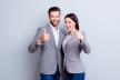 stockphototwosmilinghappybusinesspeopleinformalwearshowingthumbsupongraybackground675614236.jpg