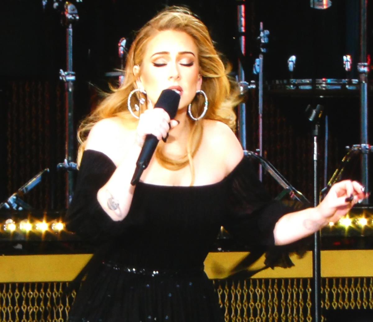 Adel u crnoj haljini peva na koncertu