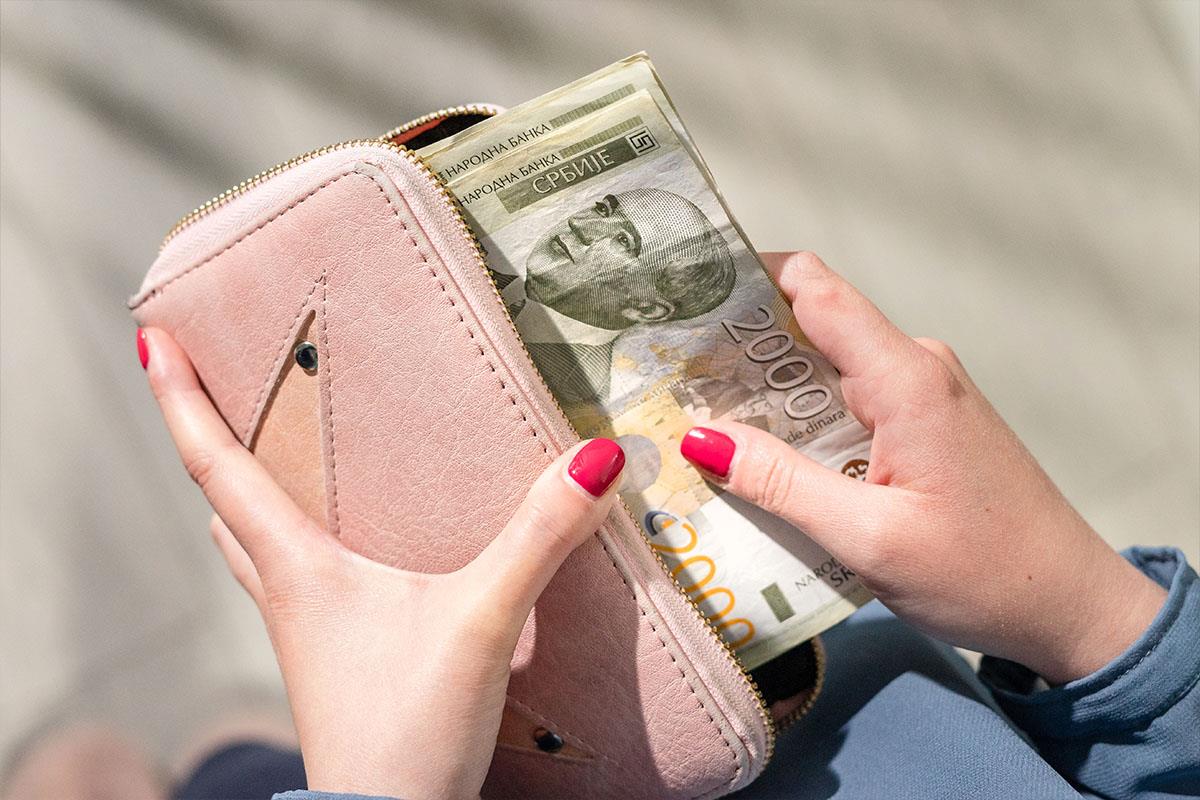 Ženska ruka stavlja 2000 dinara u rozi novčanik