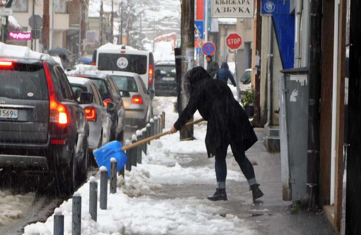 Žena čisti sneg lopatom