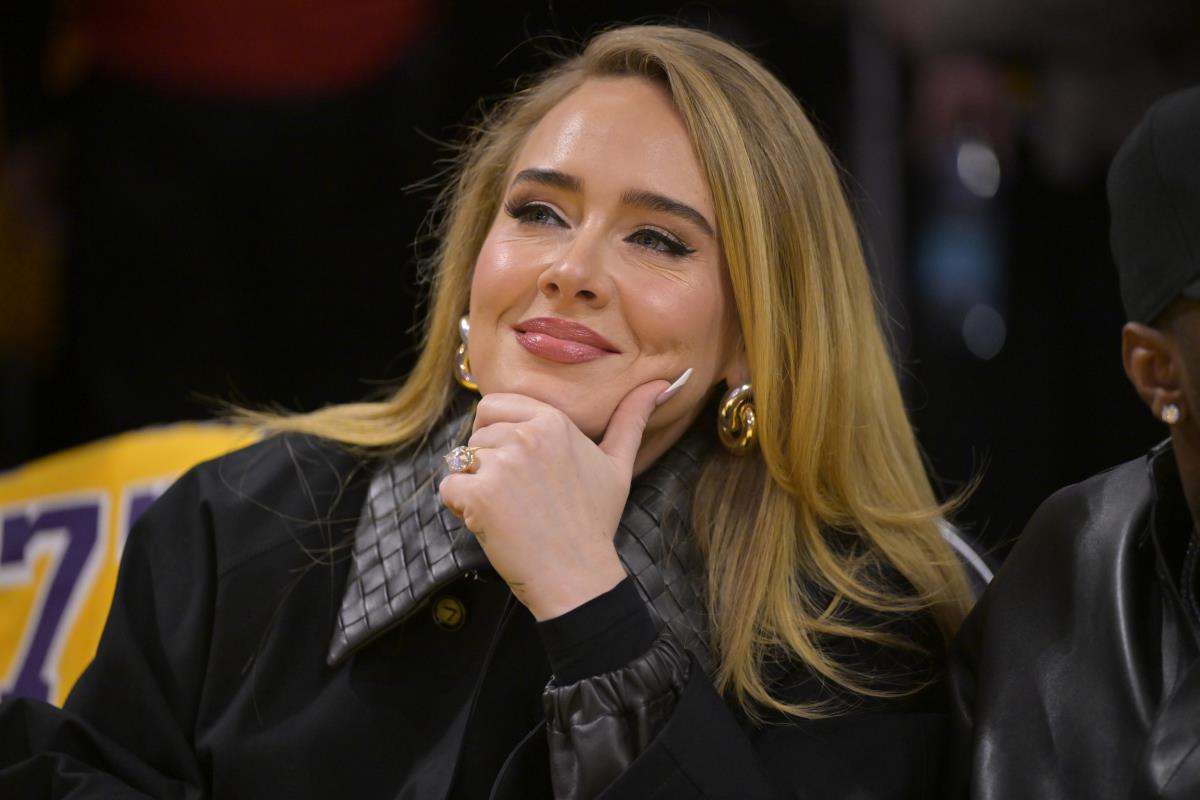 Adel u crnoj kombinaciji, smeška se i drži ruku na bradi