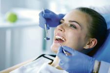 stockphotoyoungfemalepatientwithopenmouthexaminingdentalinspectionatdentistoffice1201381354.jpg