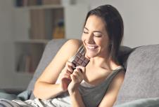 stockphotohappywomaneatingchocolateinthenightsittingonacouchinthelivingroomathome1099583195.jpg