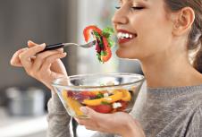 stockphotoyoungbeautifulwomaneatingfreshsaladonblurredbackground795830020.jpg