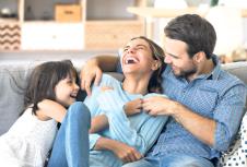 stockphotocheerfulpeoplesittingoncouchinlivingroomhavefunlittledaughterticklingmotherlaughing1236779938.jpg