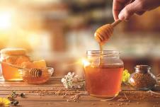 stockphotohandwithdipperpickinghoneyfromajarofhoneyjarsofhoneybeehoneycombandbeepollenon589869611.jpg