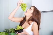 stockphotohappyyoungwomaneatinggrapesinakitchen248388628.jpg