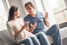 stockphotocoupleofadultsareusingasmartphoneandtalkingwhilesittingoncouchathome743857969.jpg