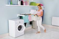 stockphotoyoungsmilingwomanwithbasketofclothesnearwashingmachineinutilityroom571658629.jpg