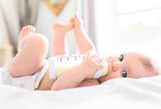 stockphotoprettybabygirldrinkswaterfrombottlelyingonbedchildweareddiaperinnurseryroom1111957652.jpg