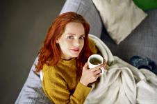 stockphotothoughtfulyoungredheadwomansittingwrappedinawarmblanketwithamugofhotteagazingupat555828808.jpg