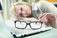 stockphotowomanwithtiredeyeswithherglassesofflyingonthetablenexttolaptopfocusedonglasses92242648.jpg