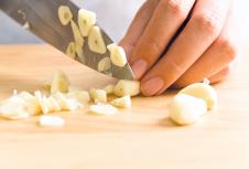 stockphotowomanchoppinggarliconwoodenboardforcooking578727862.jpg