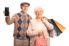 1006stockphotosmilingseniorpeoplewithamobilephoneandshoppingbagsisolatedonwhitebackground1578579991.jpg