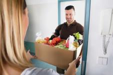 stockphotosmilingyoungwomanacceptingcardboardfullofgroceriesfromdeliveryman621969947.jpg