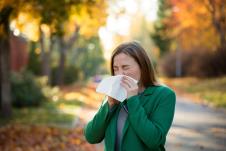 fraj-stockphotosickyoungwomanwithcoldandflustandingoutdoorssneezingwipingnosewithhandkerchief1515661988.jpg