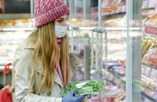 stockphotowomaninfullcoronaoutfitshoppinginsupermarketstandinginfreezersection1675657126.jpg