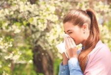 stockphotosneezingyounggirlwithnosewiperamongbloomingtreesinpark631928921.jpg