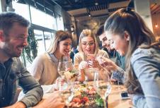 stockphotogroupofyoungfriendshavingfuninrestauranttalkingandlaughingwhilediningattable1557632120.jpg