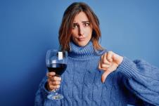 stockphotoyoungbeautifulbrunettewomandrinkingglassofredwineoverisolatedbluebackgroundwithangry1808770249.jpg