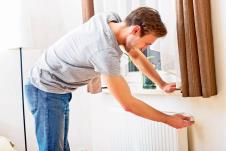 stockphotoyoungmanchangingtemperatureofradiator410638303.jpg