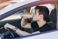 stockphotohandsomeyoungmanorteenagerdrivingcaranddrinkingwaterfromplasticbottle275461517.jpg