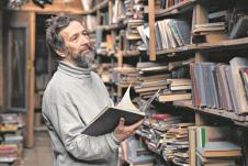 stockphotoportraitofauthenticseniormanwithbeardandgoodeyesreadingbookinthehandonbookshelf340831793.jpg