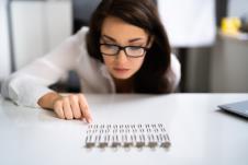 mlada žena slaže spajalice na radnom stolu/koncept OKP