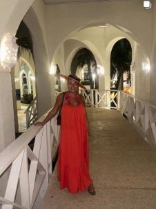 Dea Đurđević u dugoj narandžastoj haljini i šeširu, pozira u osvetljenom hodniku hotela na Kubi