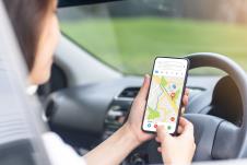 žena u kolima gleda u telefon i prati mapu, koncept GPS
