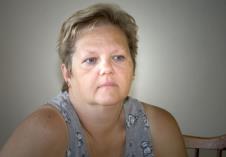 Starija žena sedi u dnevnom boravku zamišljena