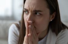 Devojka u beloj majici sklopljene ruke drži na usnama