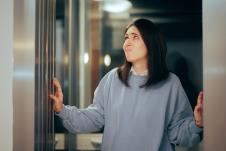 devojka u sivom duksu stoji na vratima lista sa zabrinutim izrazom lica