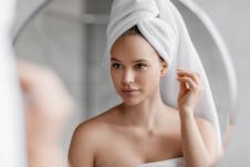mlada žena sa turbanom na glavi čisti uši u kupatilu