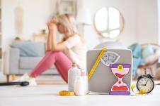 Vaga sa papirnim peščanim satom, budilnikom i tabletama na podu pored žene u menopauzi