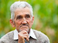 Deka u vunenom džemperu i beloj košulji se drži za bradu