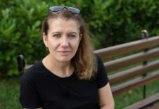 Žena sedi na klupi u parku sa naočarima na glavi
