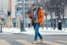 Tinejdžer drži telefomn u rukama i hoda ulicom