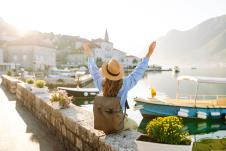 mlada žena sa rancem na leđima sedi na doku pored mora, koncept turista