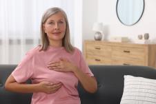 starija žena u roze majici kod kuće samopregleda dojke