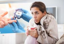 Aparat za merenje šećera u krvi/Prehlađena žena ogrnuta ćebetom drži topao čaj u ruci
