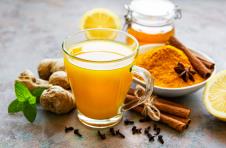 čaša napitka od kurkume, đumbira i cimeta na stolu sa sastojcima